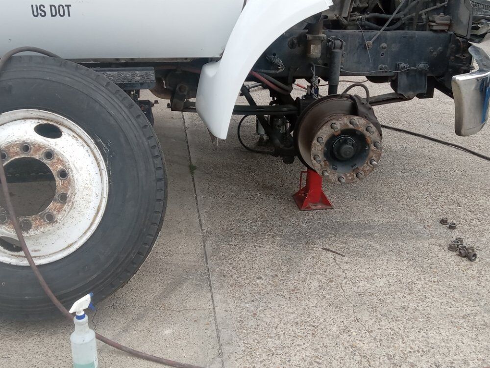 Wheel removed from a US DOT box truck on a jack stand, hub and brake exposed for service